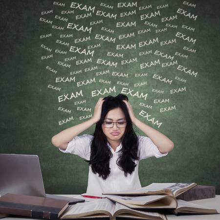 38372779-confused-teenage-girls-preparing-for-exam-while-studying-with-laptop-and-textbooks